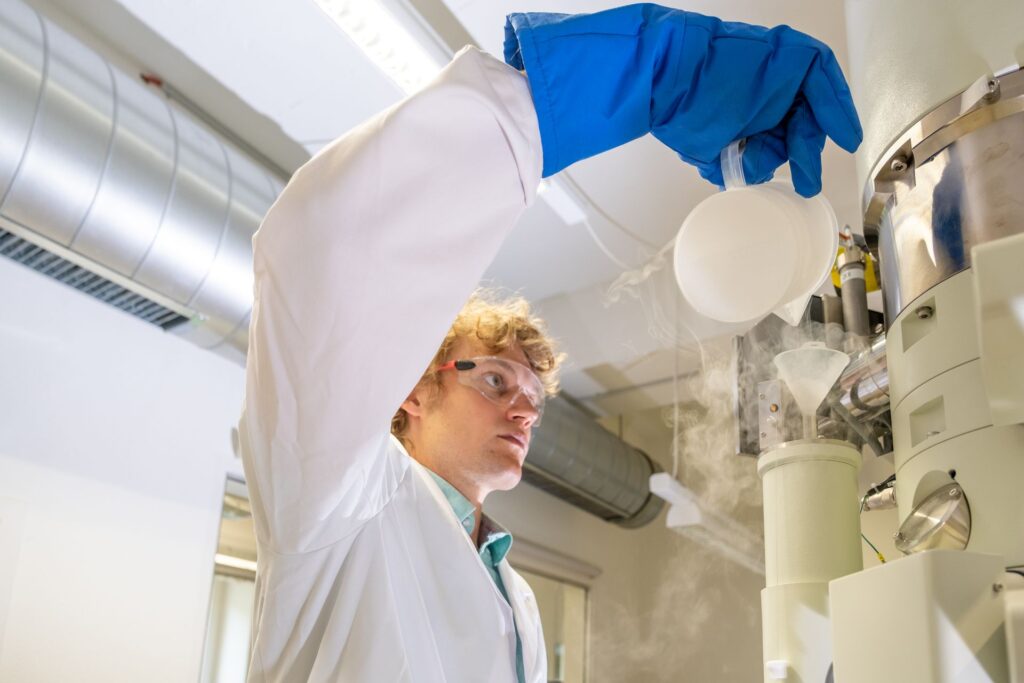Fuoco e ghiaccio: Lukas Gerken, ricercatore dell'EMPA a San Gallo, produce nanoparticelle per la radioterapia del cancro, utilizzando la cosiddetta “sintesi alla fiamma”: onde rendere visibili le minuscole particelle di metallo, il microscopio elettronico viene raffreddato a temperature di congelamento con azoto liquido (Foto: EMPA/Politecnico Federale di Zurigo)