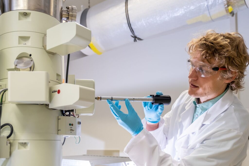 Fuoco e ghiaccio: Lukas Gerken, ricercatore dell'EMPA a San Gallo, produce nanoparticelle per la radioterapia del cancro, utilizzando la cosiddetta “sintesi alla fiamma”: onde rendere visibili le minuscole particelle di metallo, il microscopio elettronico viene raffreddato a temperature di congelamento con azoto liquido (Foto: EMPA/Politecnico Federale di Zurigo)