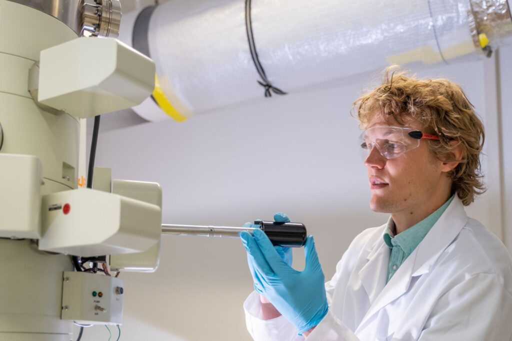 Fuoco e ghiaccio: Lukas Gerken, ricercatore dell'EMPA a San Gallo, produce nanoparticelle per la radioterapia del cancro, utilizzando la cosiddetta “sintesi alla fiamma”: onde rendere visibili le minuscole particelle di metallo, il microscopio elettronico viene raffreddato a temperature di congelamento con azoto liquido (Foto: EMPA/Politecnico Federale di Zurigo)