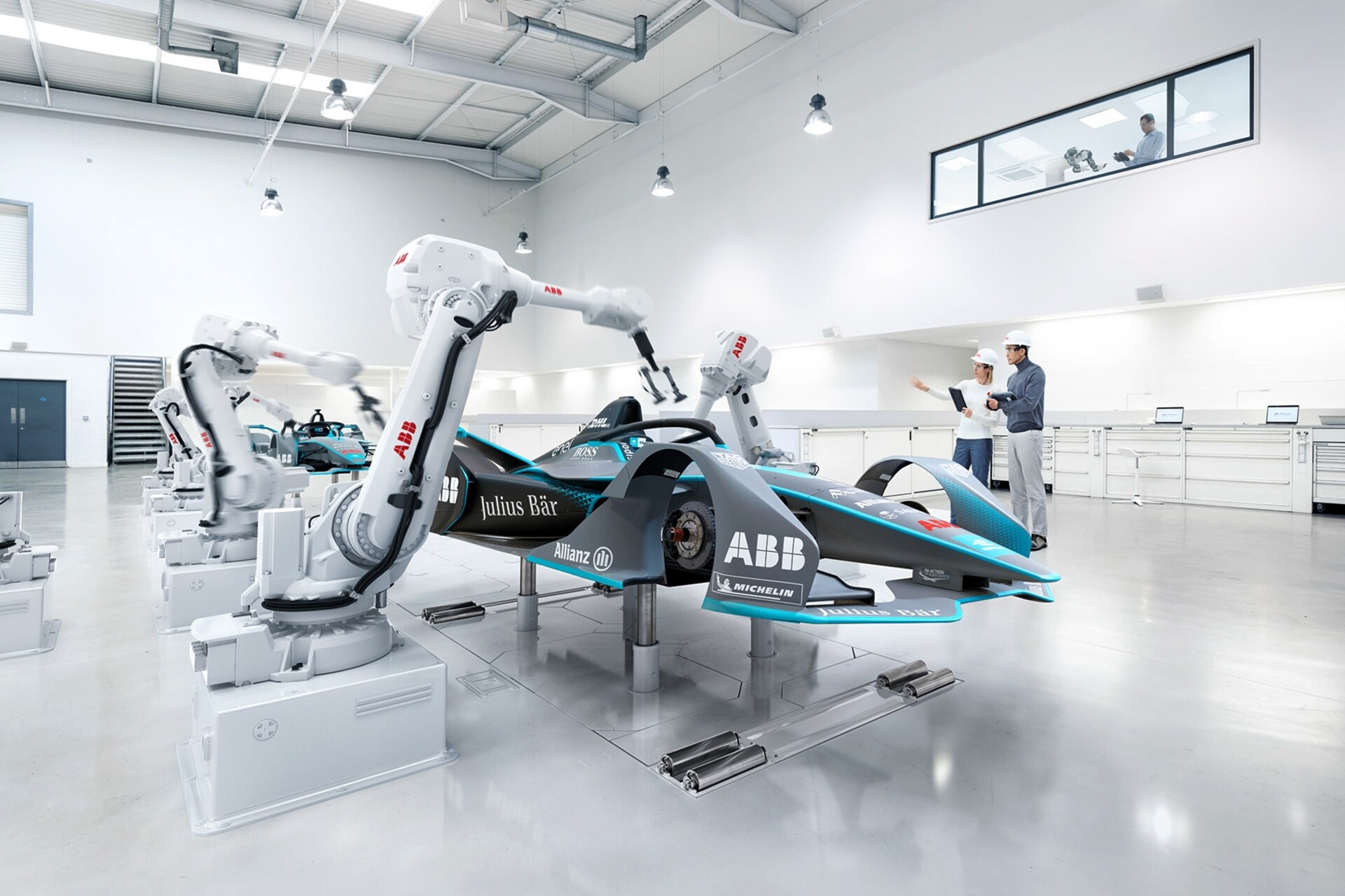 Una monopostio di Formula E in livrea istituzionale accanto a ai robot di Formula E