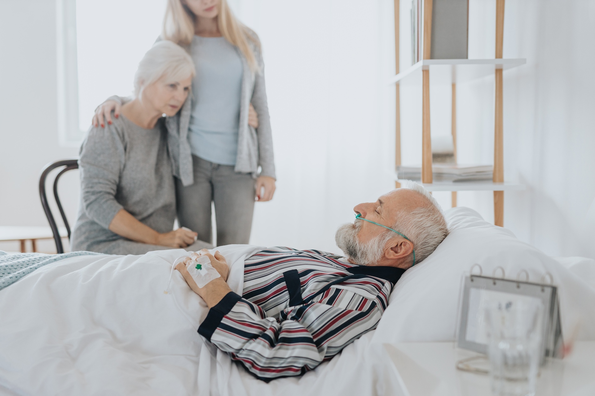 Assistenza sanitaria: un paziente in stato di incoscienza vegliato dai propri familiari in un letto d'ospedale