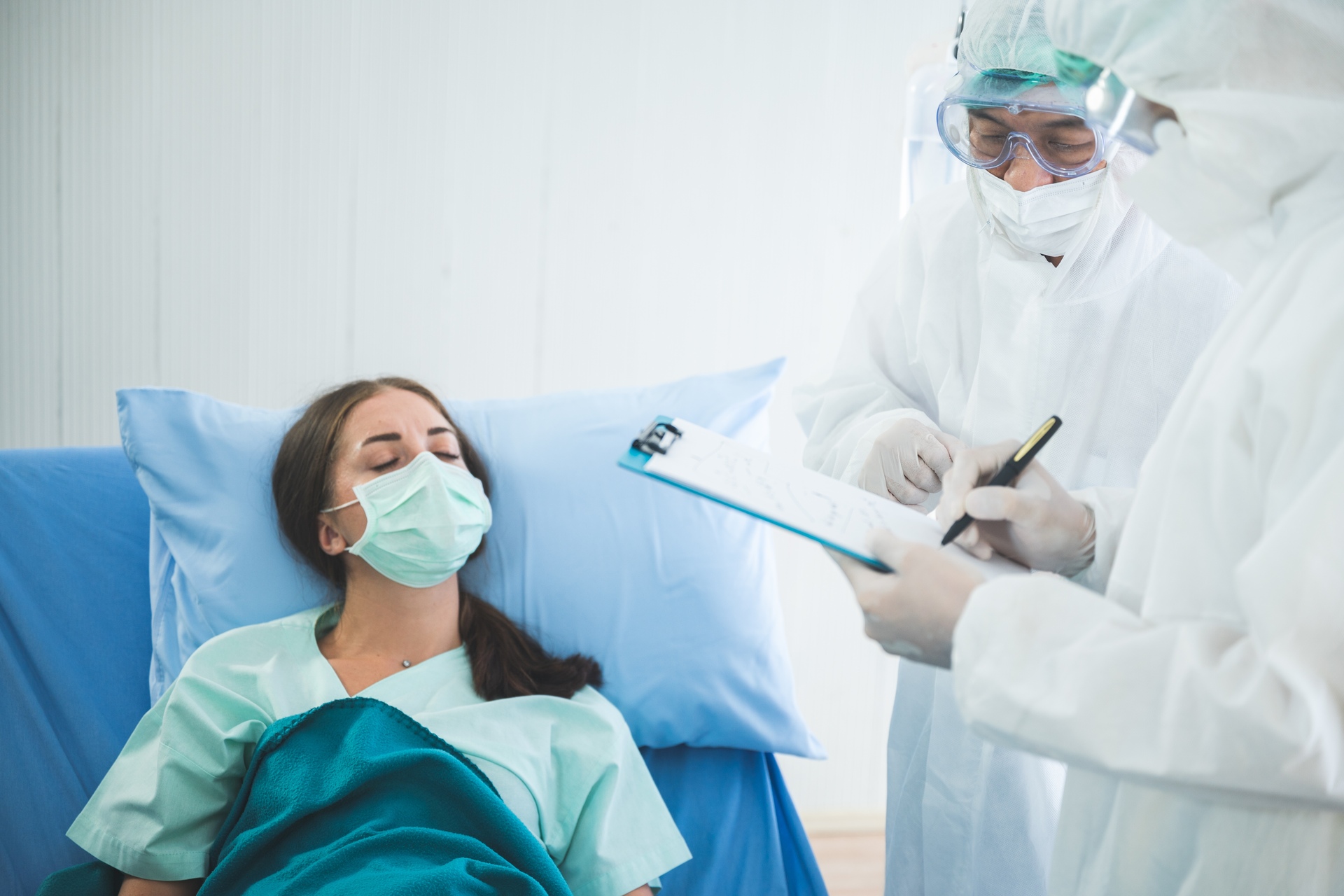 Assistenza sanitaria: una paziente contagiosa racconta i propri sintomi a medici con tute anticontaminazione