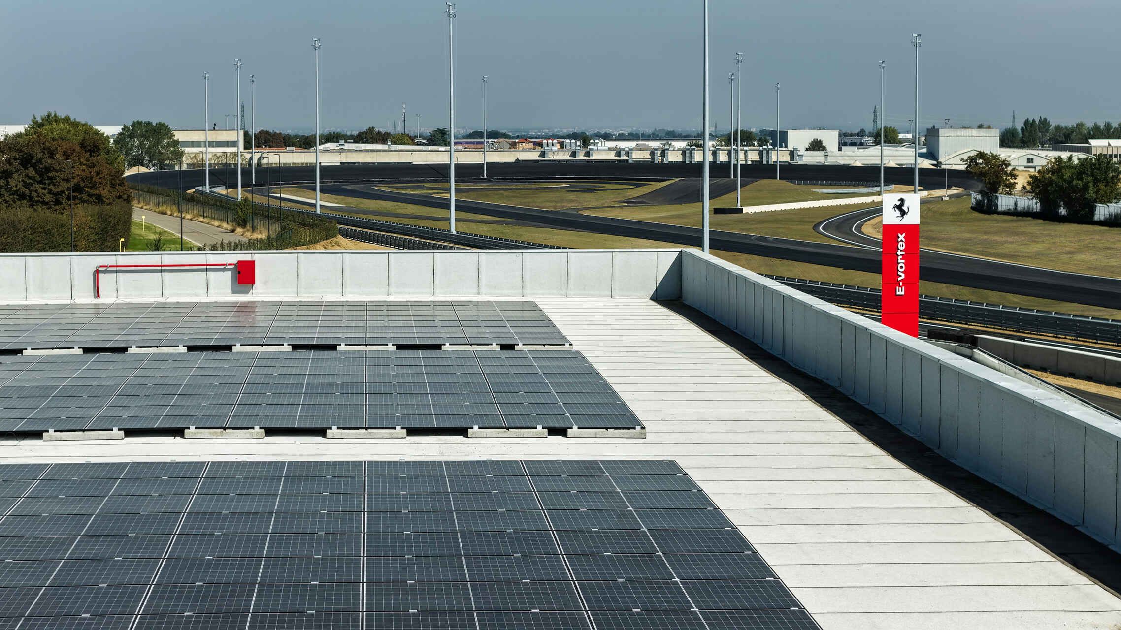 Ferrari e-Vortex: veduta dal tetto di un edificio Ferrari con pannelli fotovoltaici che riflettono la luce del sole, simbolo di sostenibilità e innovazione nel nuovo circuito di collaudo di Maranello