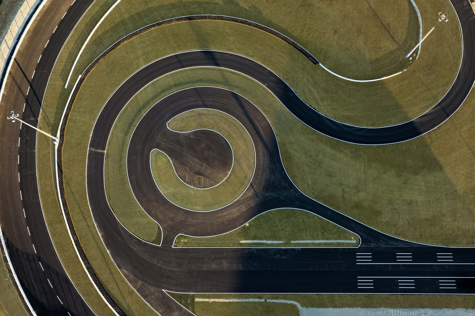 Ferrari e-Vortex: curva sopraelevata e sezione tecnica viste dall’alto, con superfici in porfido e tratti disconnessi per analisi di comfort, vibrazioni e risposta strutturale dei veicoli