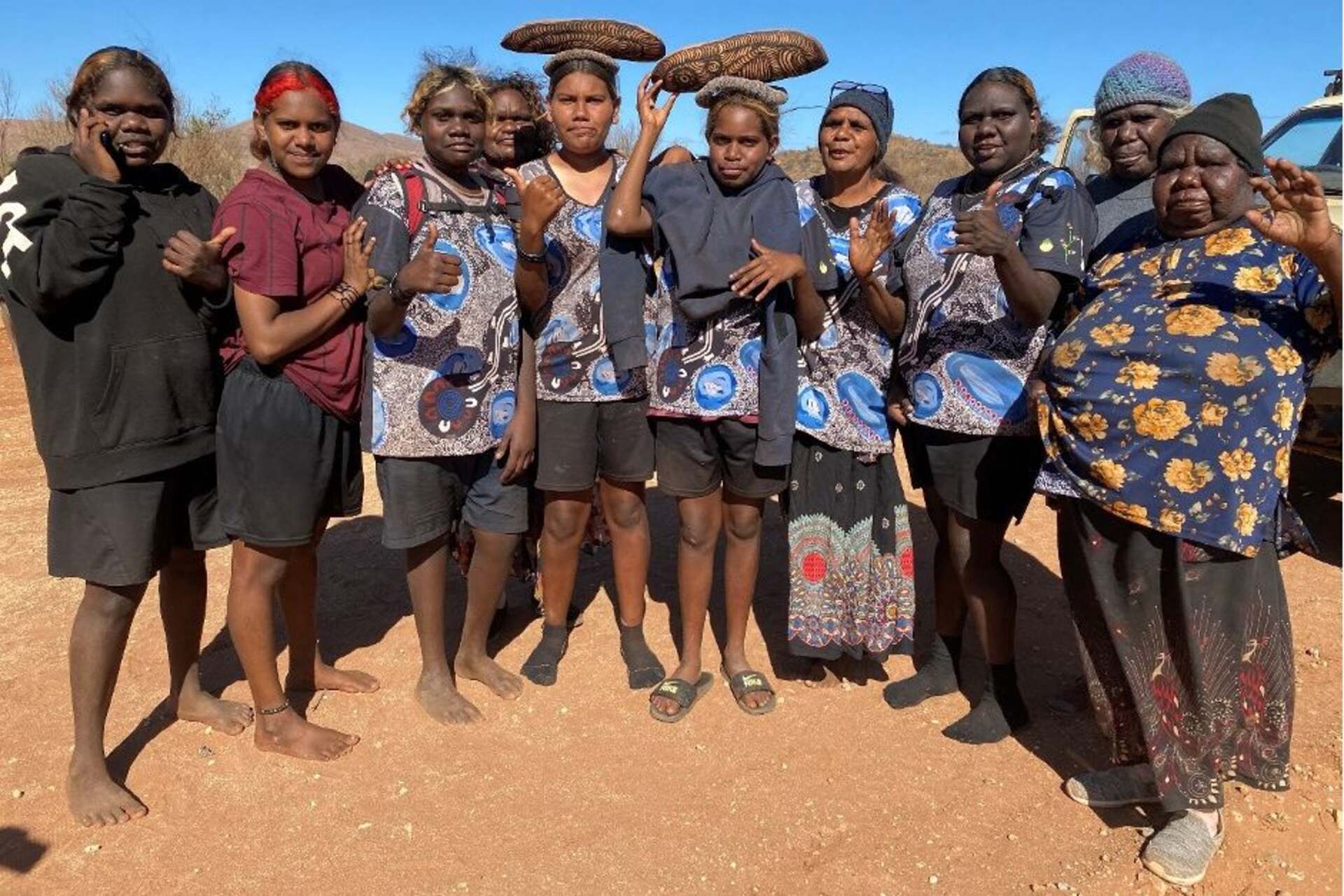 Persone ritratte insieme davanti a Uluṟu, tra membri della comunità locale e collaboratori di Bruce Munro: l’immagine riflette dialogo culturale, cooperazione e partecipazione alla realizzazione di Field of Light