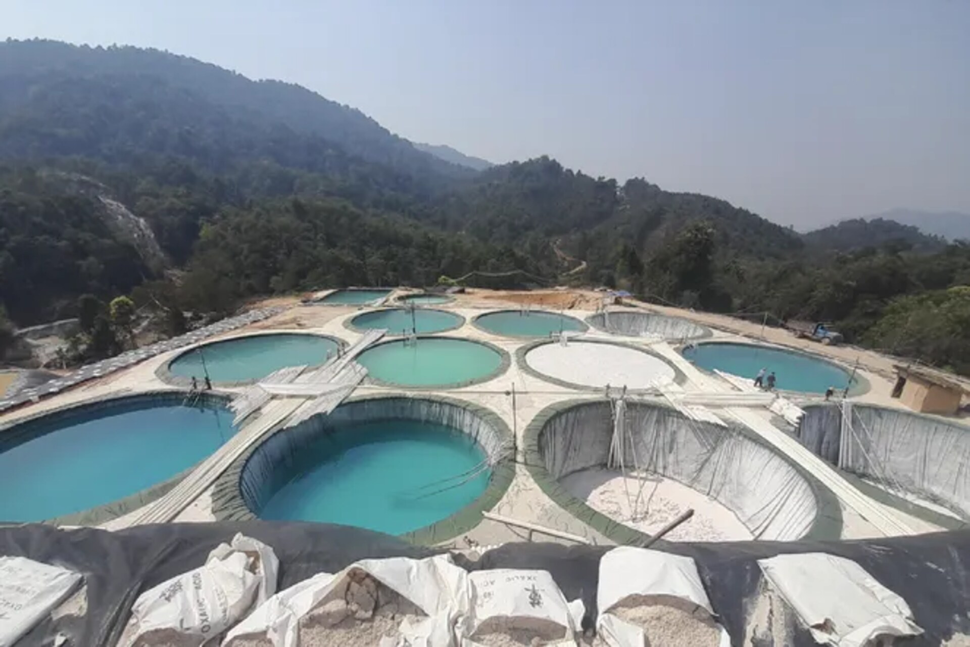 Stato Kachin: area di estrazione di terre rare nel nord del Myanmar con perforazioni per l’in situ leaching, vasche di raccolta e paesaggi montani interessati da attività minerarie legate ai minerali critici per la transizione energetica globale