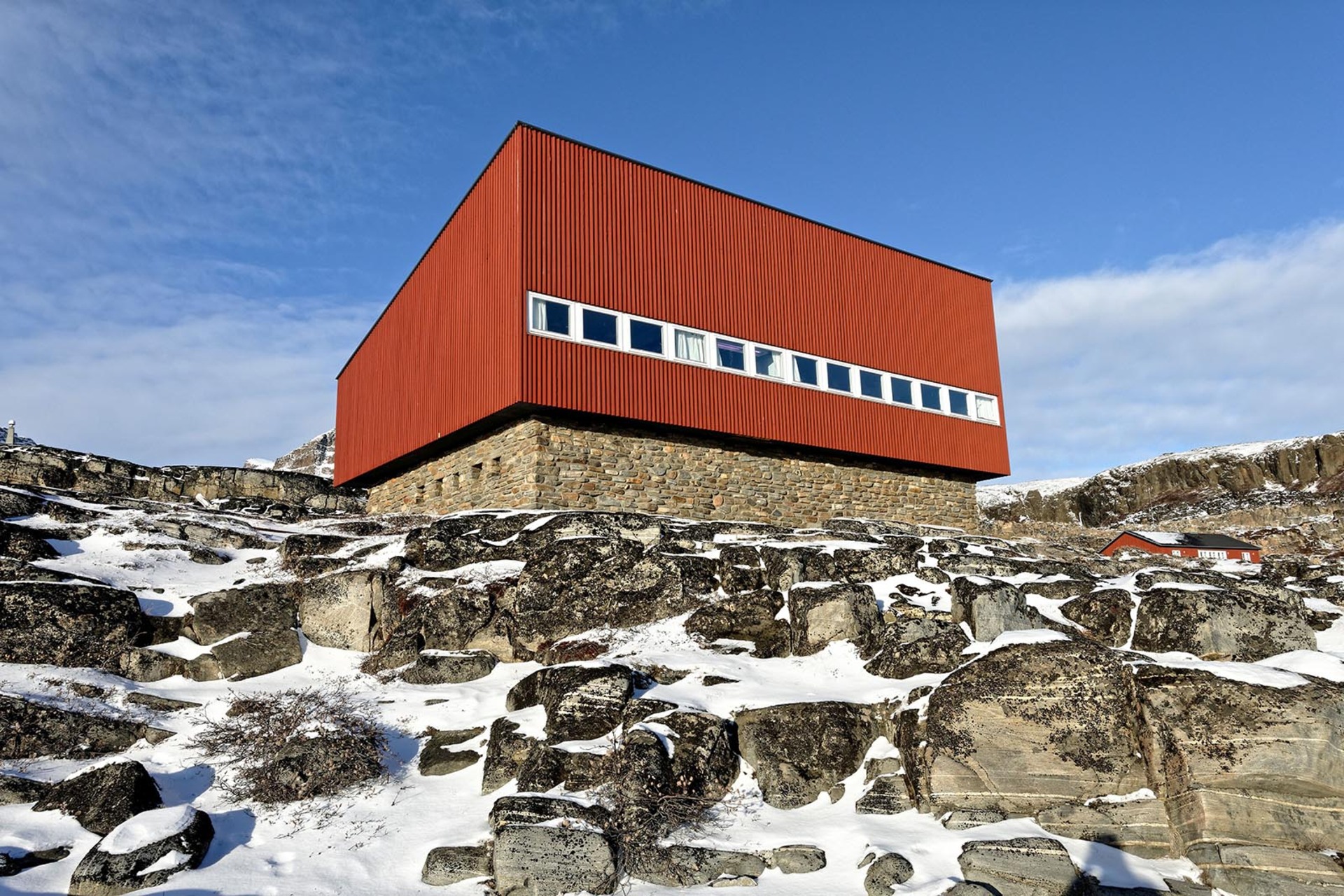Dansk arktisk station: røde bygninger midt i sne, klipper og bjerge på Diskoøen, i et fjerntliggende landskab hvor klimaforskning og hverdagsliv mødes.