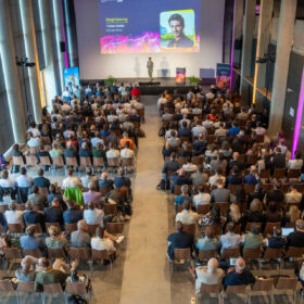 AI Mountain Summit: gruppo di partecipanti all’esterno del GALAAXY tra banner dell’evento, paesaggio alpino e temi di innovazione digitale