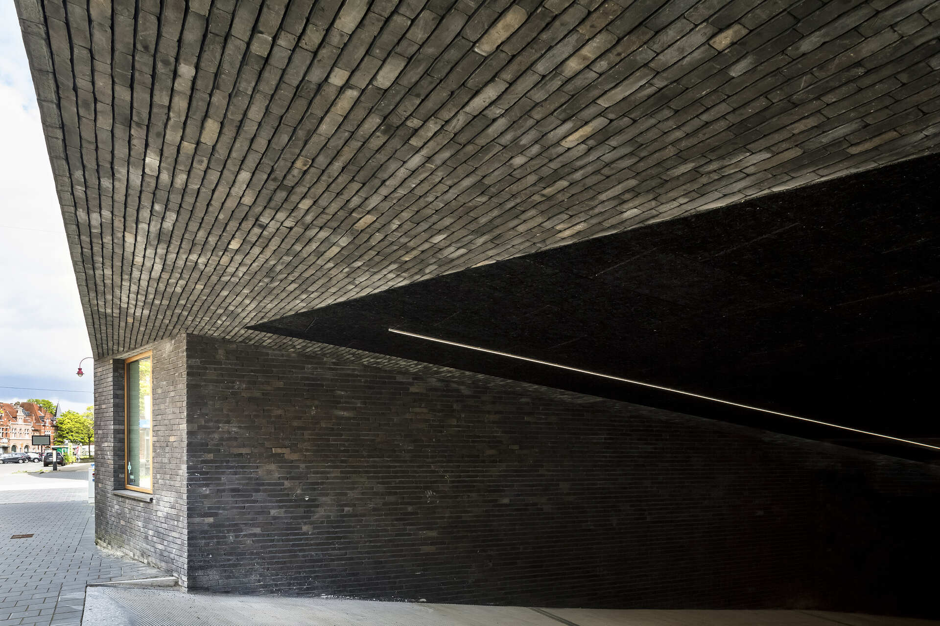 Snake Building: edificio a uso misto nel centro di Aarschot, con murature in laterizio, cornici lignee, coperture articolate e affacci sulla nuova piazza del quartiere De Torens