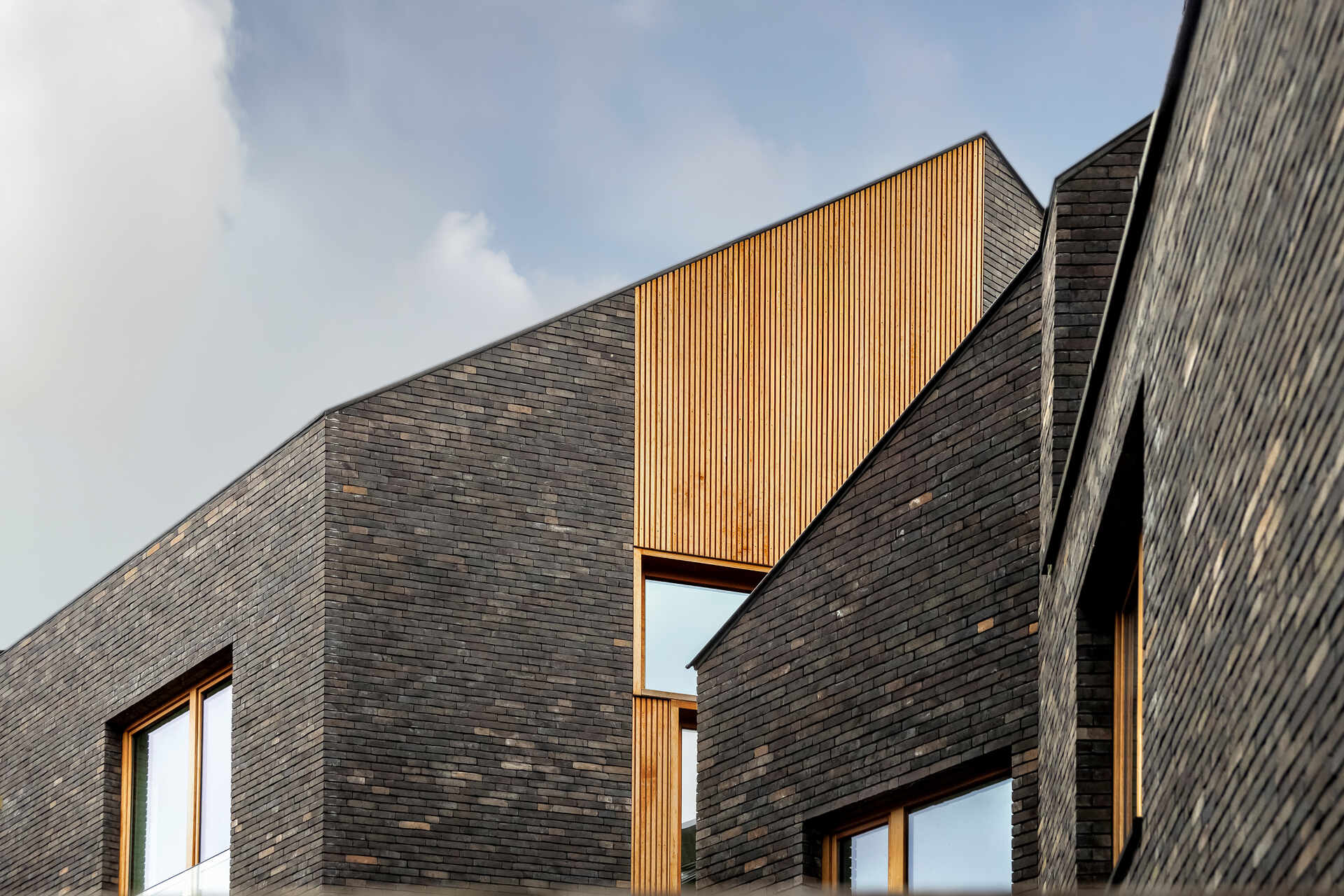 Snake Building: progetto architettonico in Belgio che rielabora i tetti e le facciate tradizionali di Aarschot attraverso una composizione contemporanea di mattoni, legno, logge e terrazze