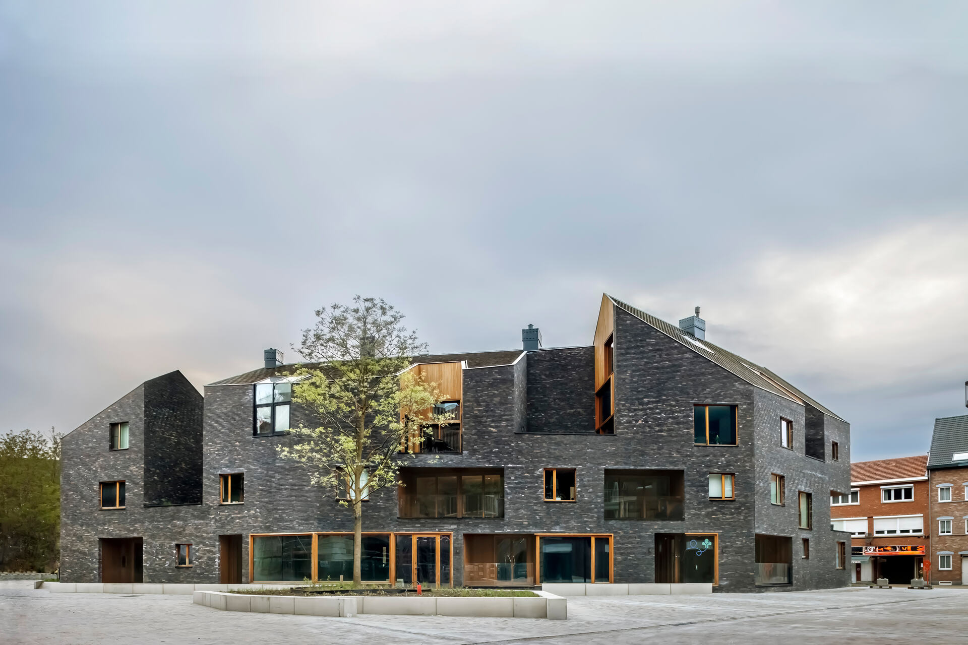 Snake Building: edificio contemporaneo nel quartiere De Torens, con piazze, percorsi, logge e coperture inclinate che reinterpretano la forma urbana e l’identità architettonica di Aarschot