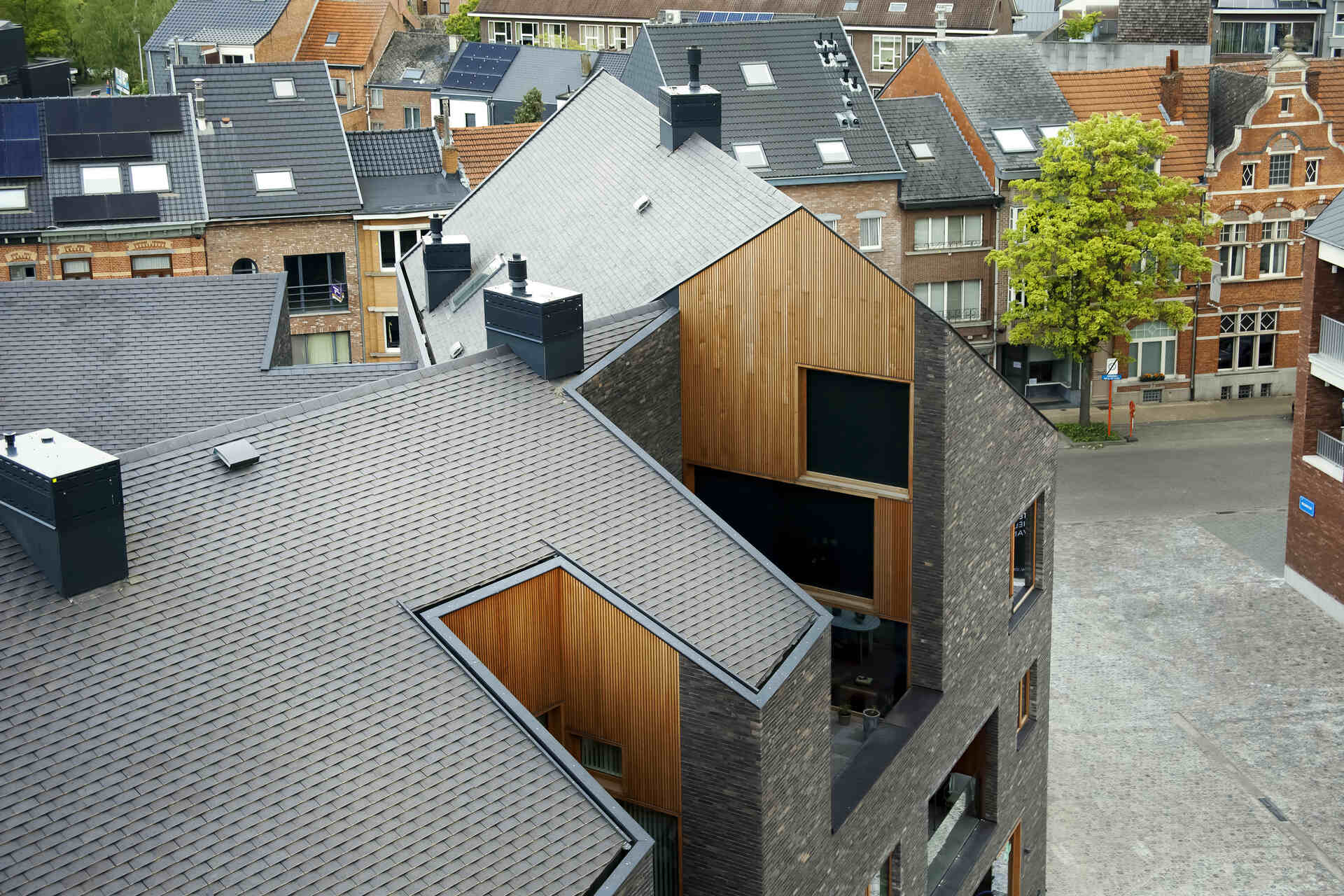 Snake Building: intervento di rigenerazione urbana ad Aarschot, in Belgio, dove residenze, commercio e spazio pubblico si integrano attraverso facciate continue, aperture e volumi irregolari